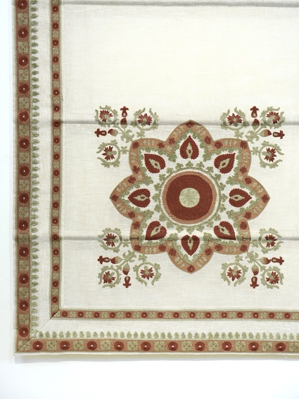Cream-colored fabric blind with a central floral mandala pattern